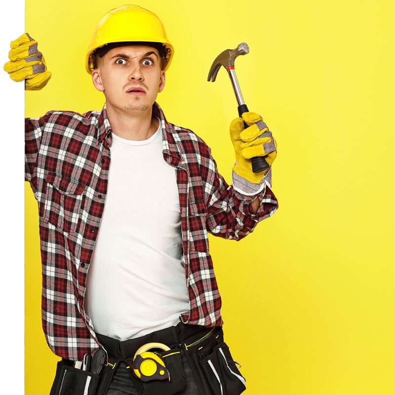 professional builder in work clothes in helmet holding hammer. copy space for text